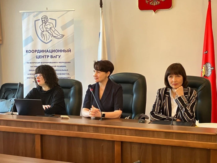 О. Блинова (сидить біля червоного прапора) на одній з наукових конференцій в рф. Фото окупаційного телеграм-каналу  самопроголошеного херсонського вишу